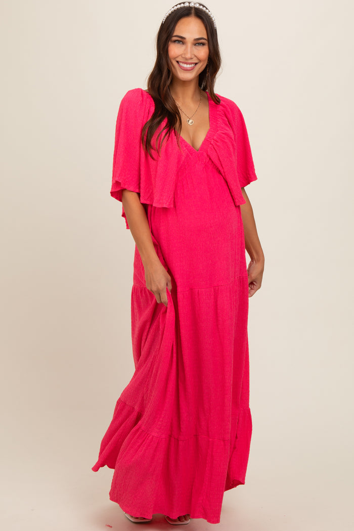 woman wearing a bright pink maternity maxi dress with a matching lightweight cardigan and a visible baby bump