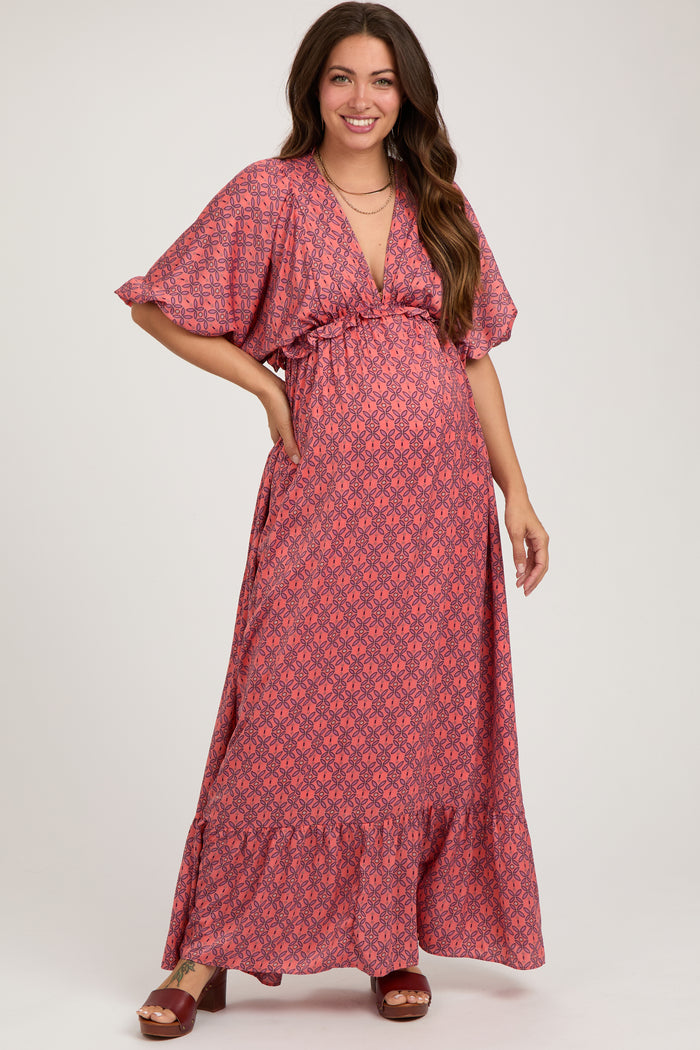 woman wearing a pink floral maternity maxi dress with a deep V-neck and ruffled hemline, showing her baby bump