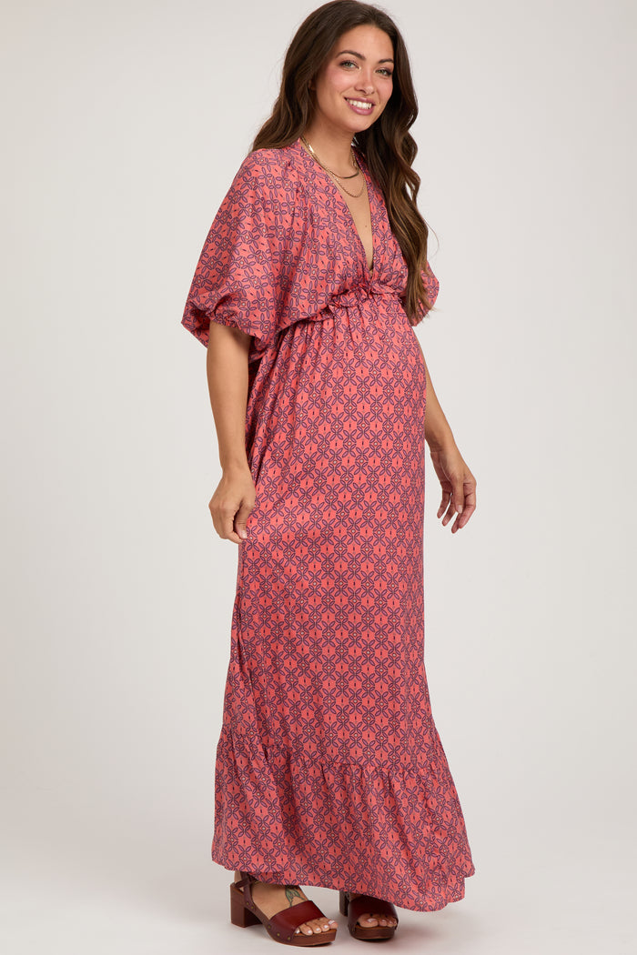 woman wearing a red floral maternity maxi dress with a v-neckline and short sleeves, showcasing her baby bump