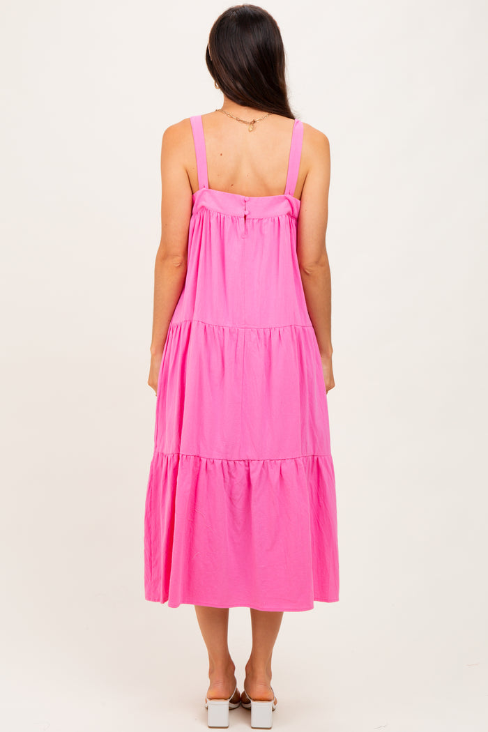 woman wearing a bright pink tiered midi dress with adjustable straps, viewed from the back