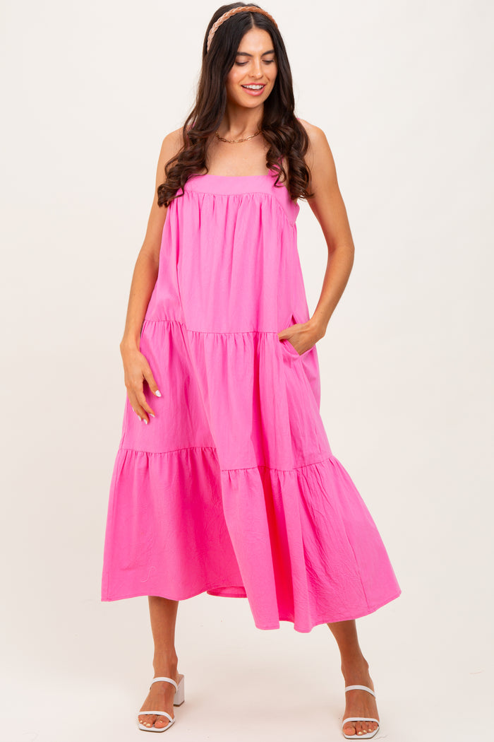 woman wearing a bright pink tiered maxi dress with pockets and a relaxed fit