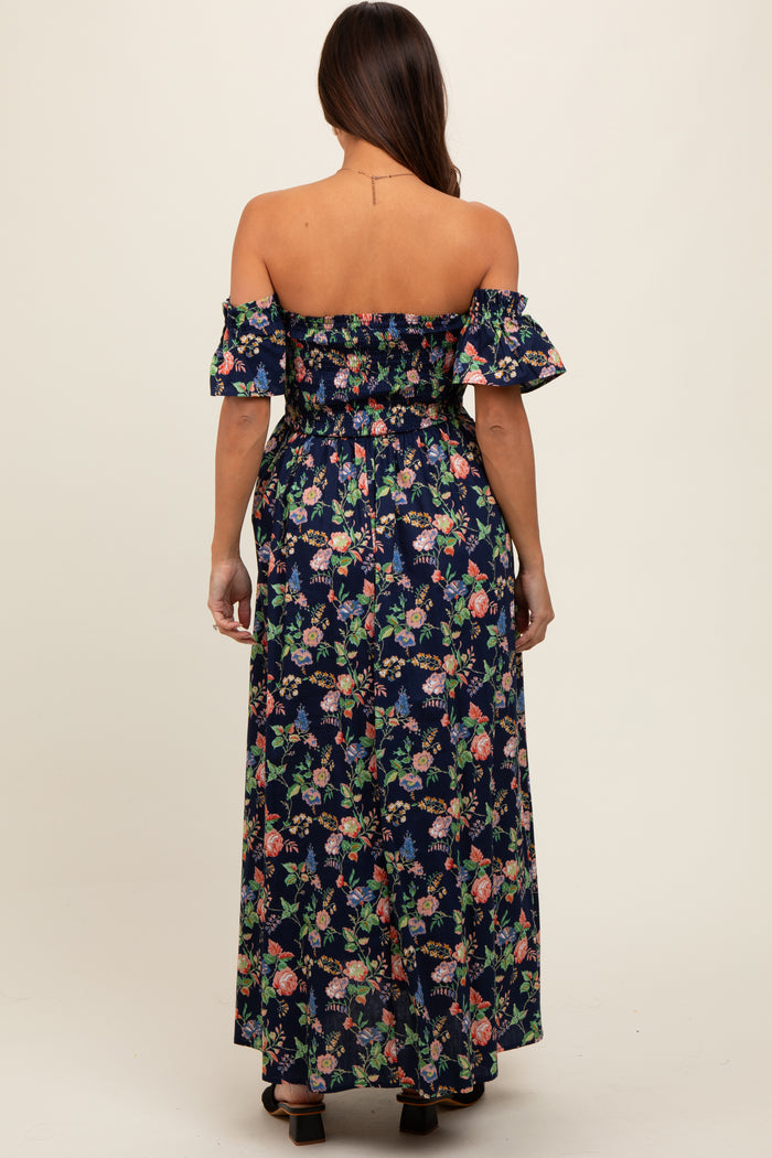 woman wearing a navy blue off-shoulder floral maternity maxi dress with wide sleeves and a fitted waist, showing her baby bump