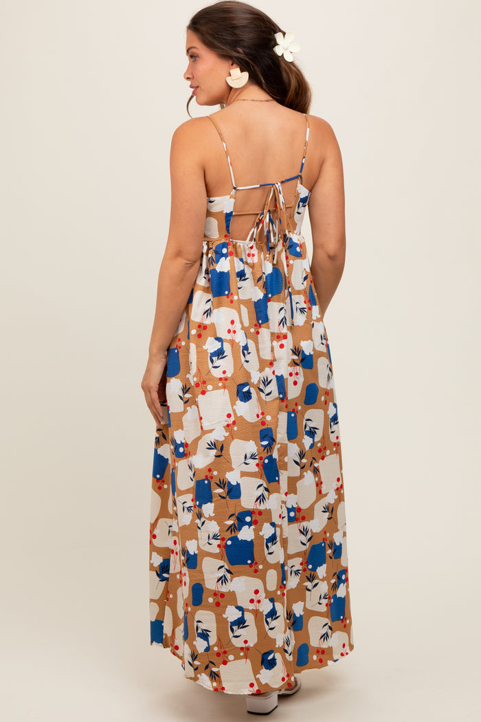 woman wearing a colorful patterned maternity maxi dress with adjustable spaghetti straps and an open back design