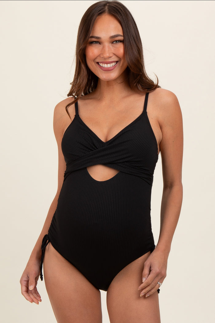 woman wearing a black maternity swimsuit with a twisted front and cut-out detail, showing her baby bump