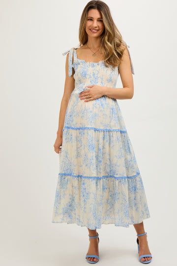woman wearing a light blue floral maternity maxi dress with adjustable straps and holding her baby bump