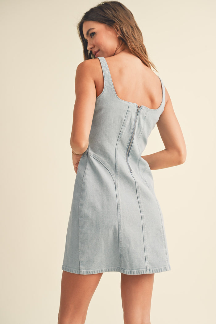 woman wearing a light blue denim mini dress with a square neckline and a zip closure at the back