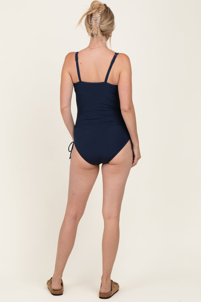 woman wearing a navy blue ribbed one-piece swimsuit with adjustable straps and a low back design