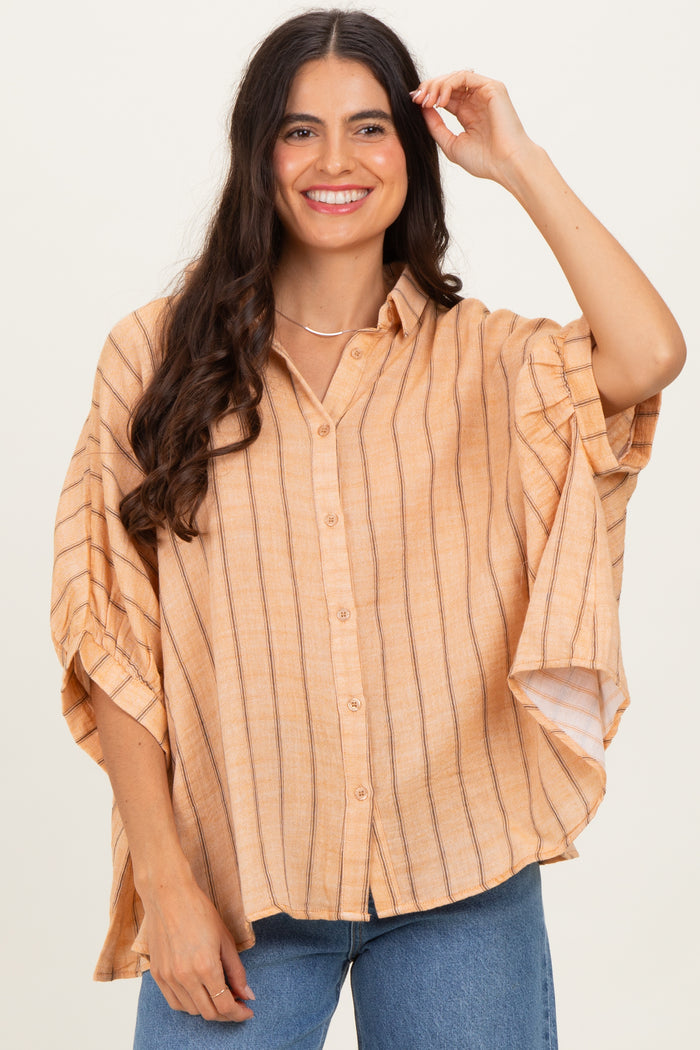 woman wearing a light orange striped oversized button-up shirt with short sleeves and a relaxed fit