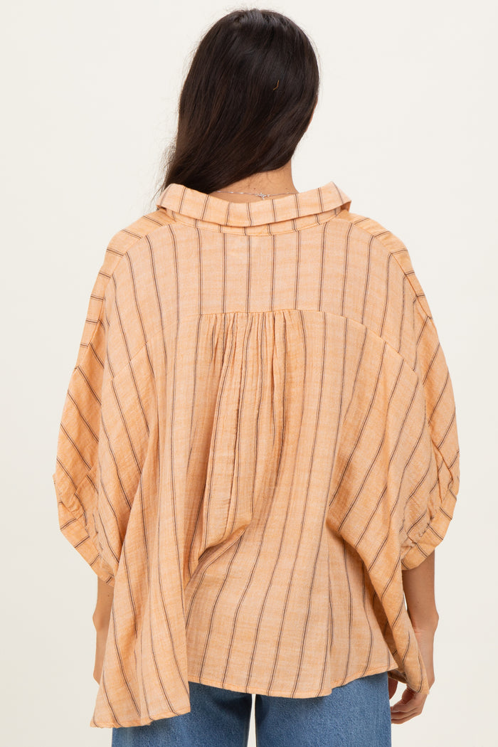 woman wearing a peach striped oversized blouse with a buttoned collar and gathered back detail