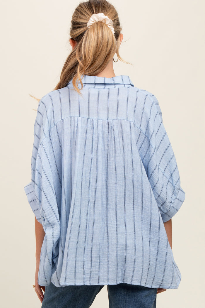 woman wearing a light blue striped maternity top with a loose fit and rolled-up sleeves, viewed from the back