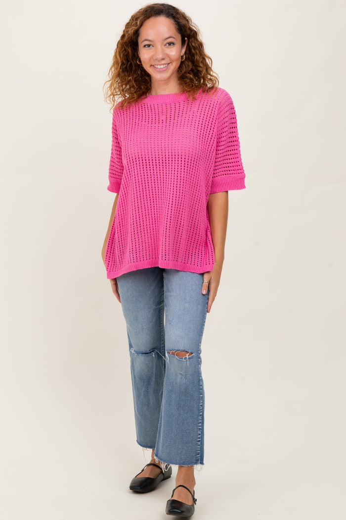 woman wearing a bright pink oversized knit sweater and light wash ripped jeans