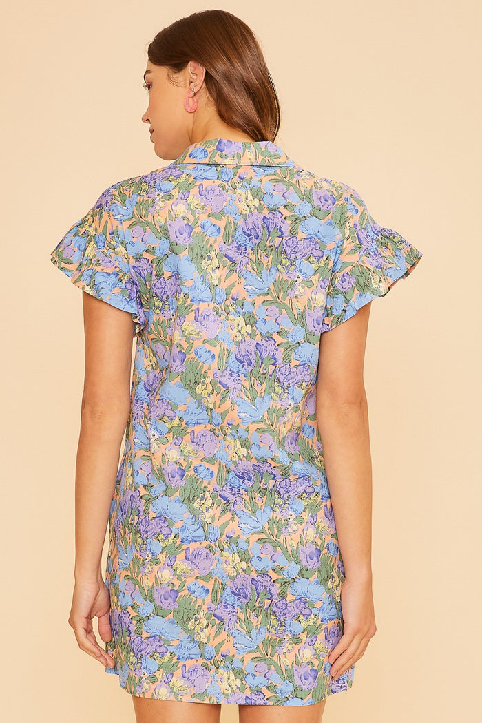 woman wearing a floral print short sleeve dress in pastel colors, showing the back view