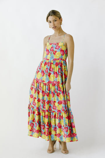 woman wearing a colorful floral maxi dress with a tiered design and adjustable spaghetti straps