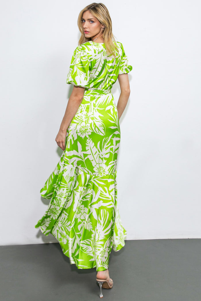 woman wearing a green floral maxi dress with puff sleeves and a ruffled hem, seen from the back