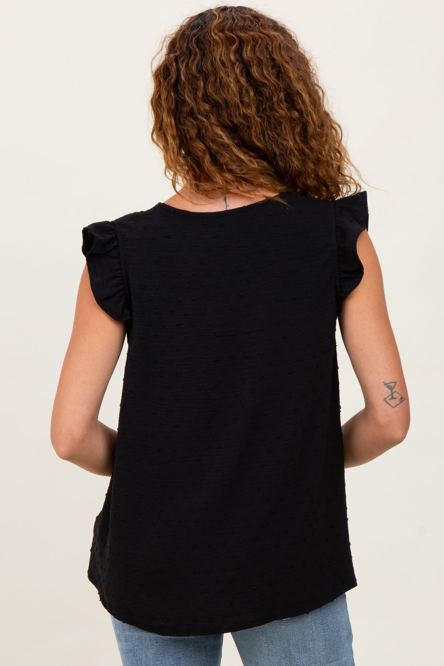 woman wearing a black sleeveless top with ruffle sleeves, viewed from the back