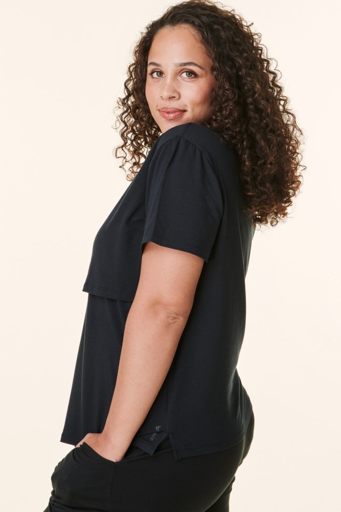 woman wearing a black short sleeve top with a layered design and relaxed fit