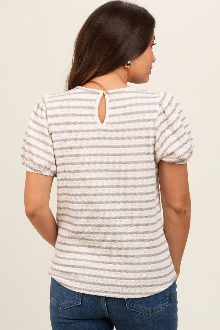 woman wearing a cream and beige striped maternity top with puff sleeves and a back keyhole detail