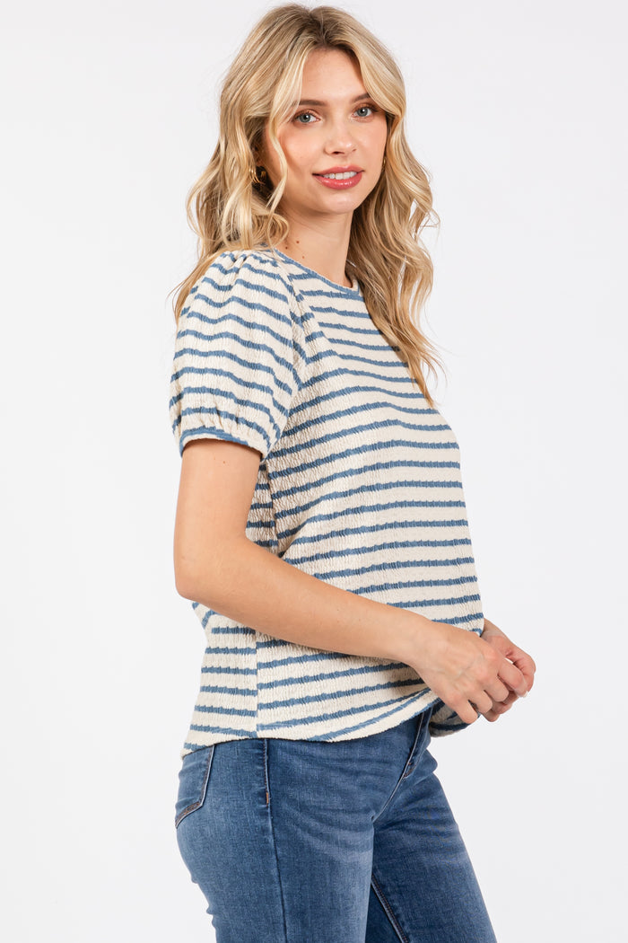 woman wearing a cream and blue striped short sleeve top with puff sleeves and paired with blue jeans