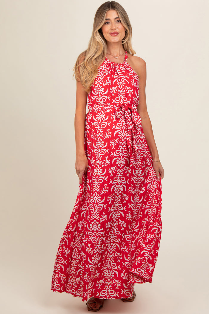 woman wearing a red floral print maternity maxi dress with a halter neckline and a flowing silhouette