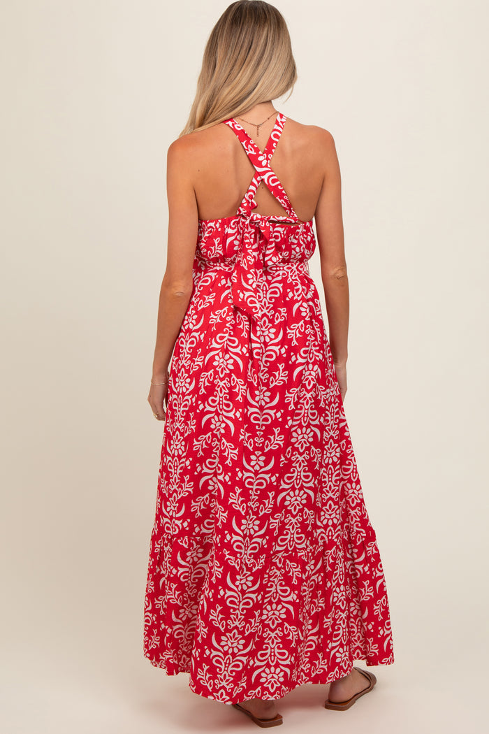 woman wearing a red floral maxi maternity dress with a crisscross back design