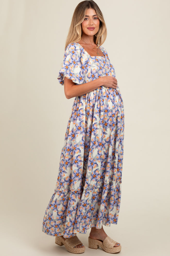 woman wearing a floral print maternity maxi dress and holding her baby bump