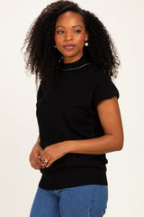woman wearing a black short sleeve sweater with a high neck and ribbed hem, styled with blue jeans