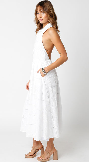 woman wearing a white sleeveless maxi dress with a high neckline and side pockets, styled with tan heels