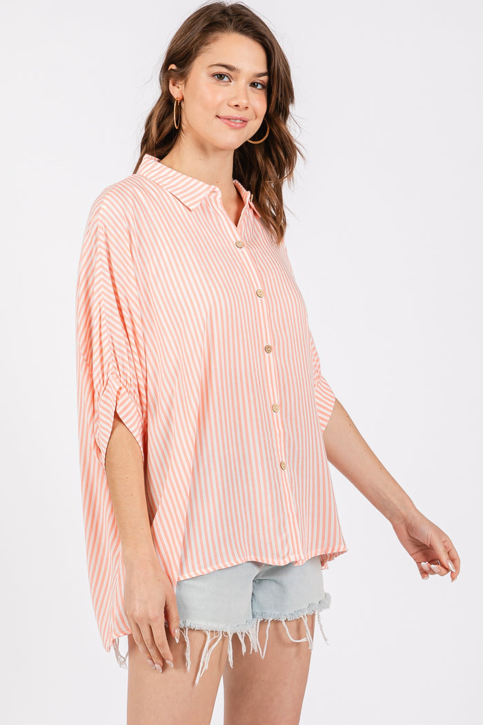 woman wearing a coral and white striped button-up shirt with short sleeves and distressed denim shorts