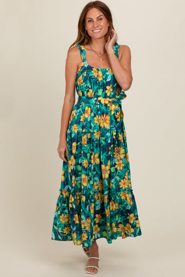 woman wearing a tropical floral maxi dress with a ruffled bodice and tiered skirt, smiling on a neutral background