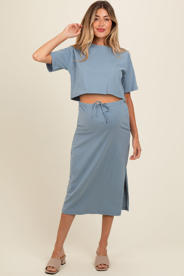woman wearing a light blue maternity two-piece set with a cropped top and a midi skirt, featuring a side slit and drawstring waist