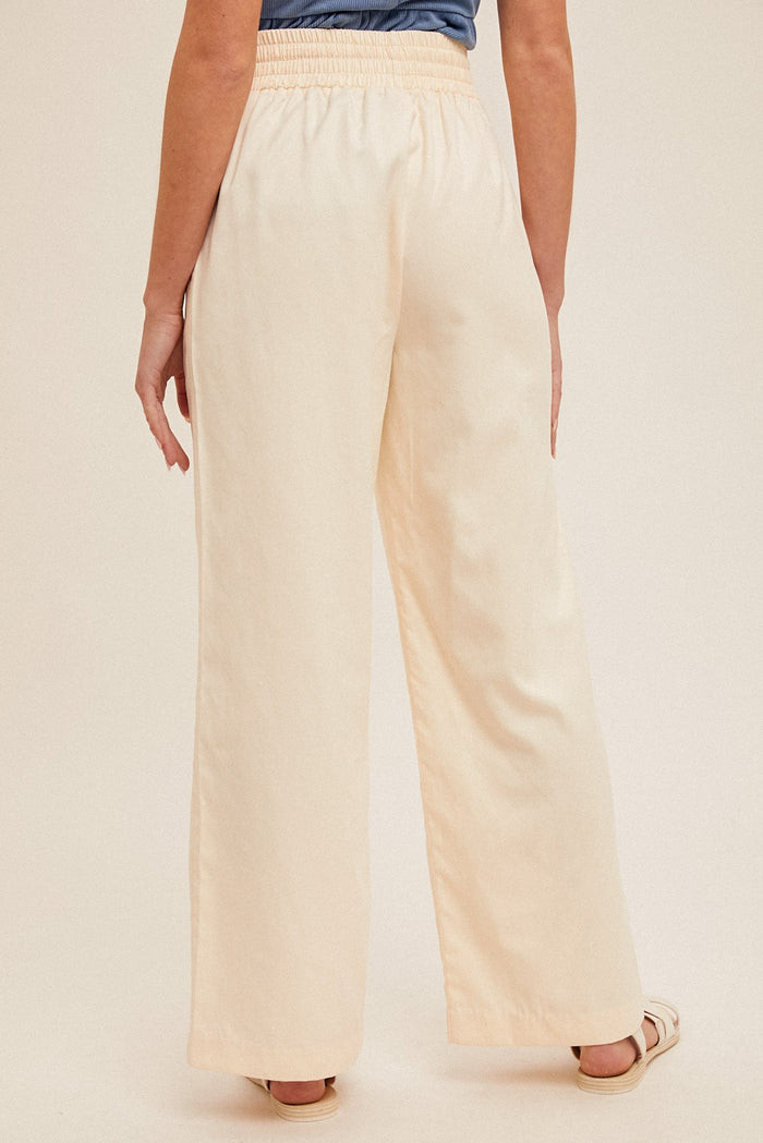 woman wearing back view of light cream wide-leg pants with an elastic waistband