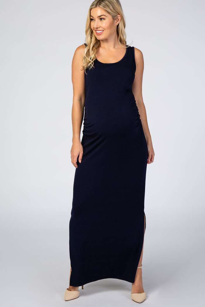 blonde woman wearing a navy blue sleeveless maternity maxi dress with side slits and tan heels