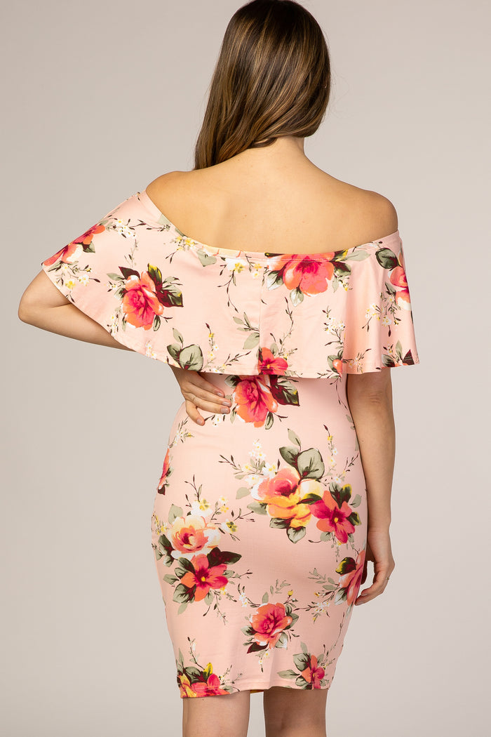 Back view of a woman wearing a light pink off-the-shoulder floral ruffle maternity dress