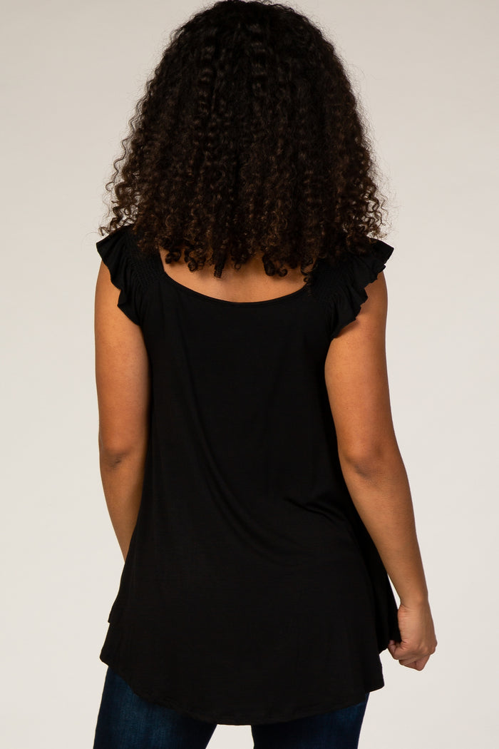 Back view of a woman with curly hair wearing a black ruffle sleeve top and blue jeans