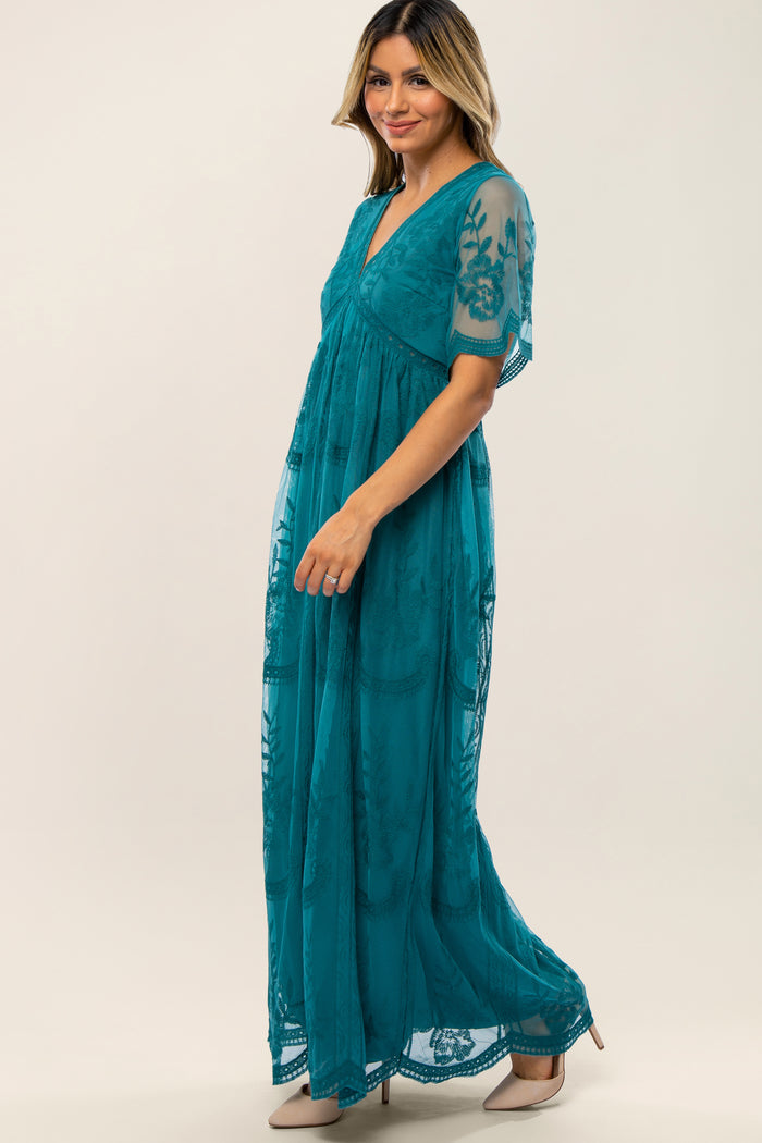 woman wearing a teal maxidress with sheer embroidered sleeves and a v-neckline