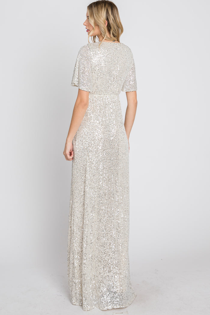 woman wearing a silver sequin evening gown with short flutter sleeves and a flowing skirt, viewed from the back