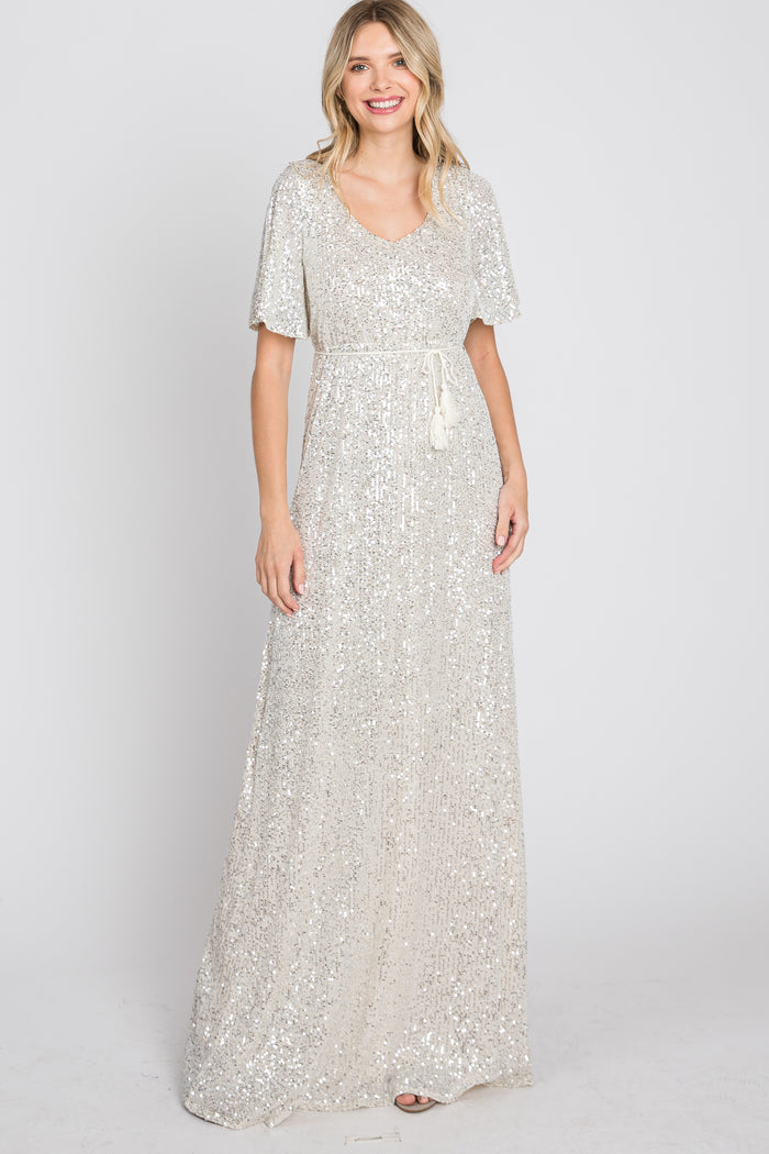 woman wearing a silver sequined maxi dress with a v-neckline and short flutter sleeves