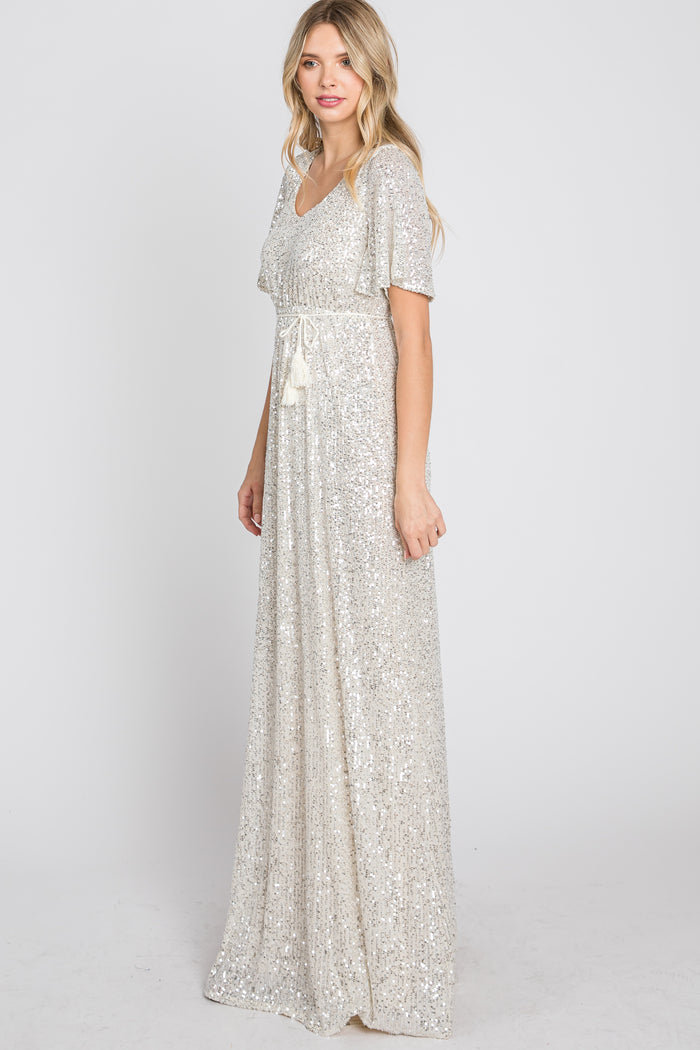 woman wearing a shimmering silver sequin maxi dress with a v-neckline and short flutter sleeves