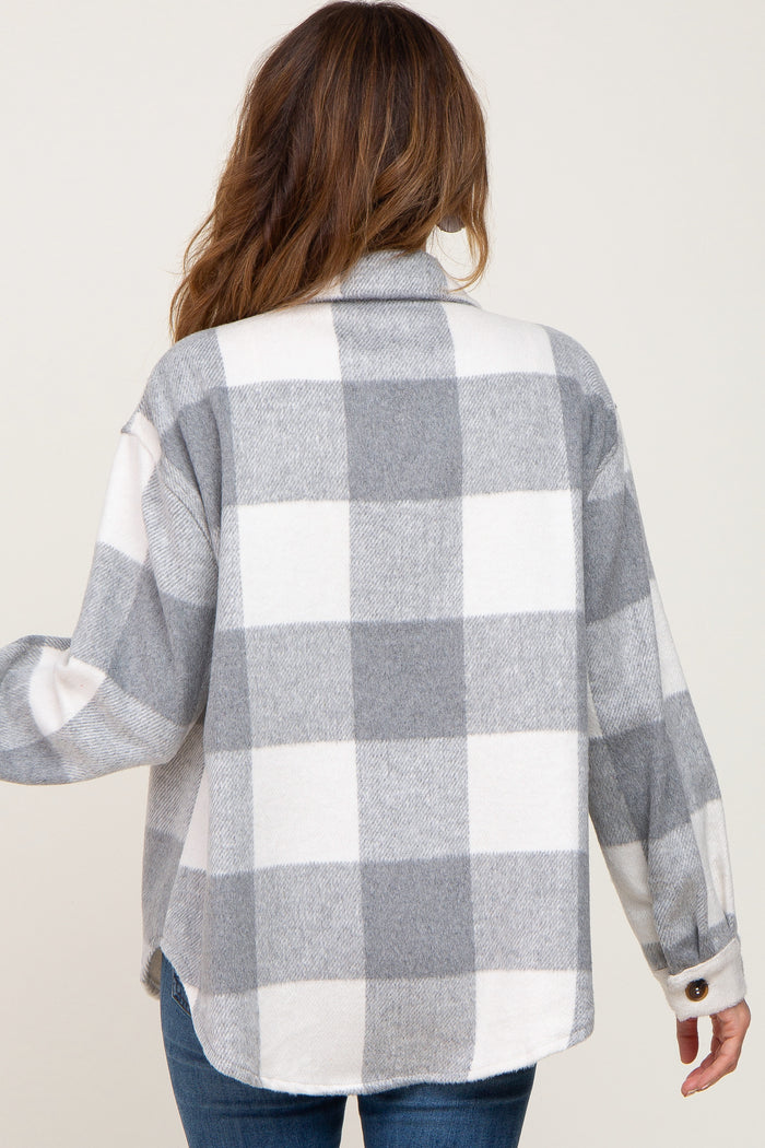 Back view of a woman wearing a grey and white buffalo plaid flannel shirt jacket with blue jeans