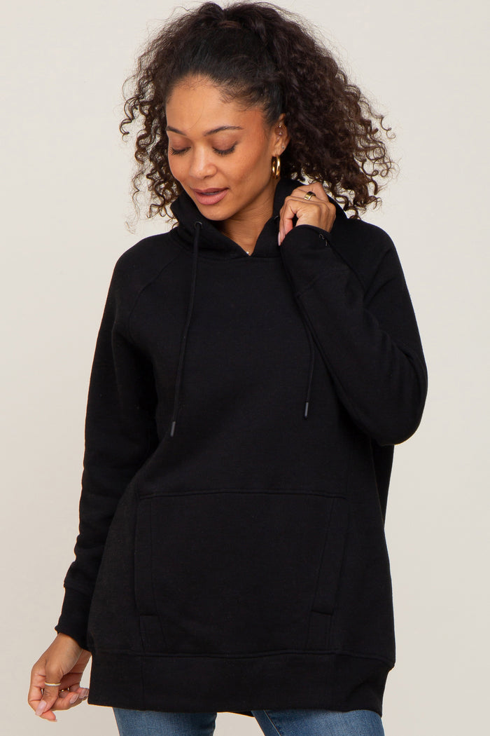 woman with curly hair wearing a black pullover hoodie with a front pocket and drawstrings