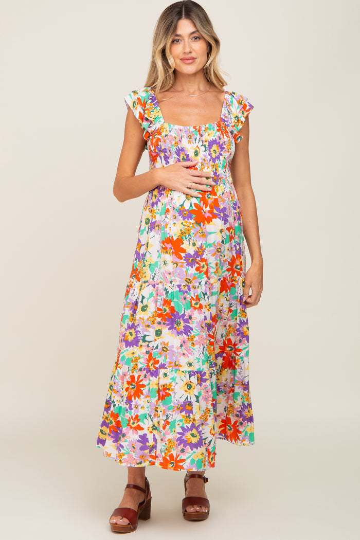 pregnant woman in a colorful floral smocked maternity midi dress with ruffle sleeves and brown sandals