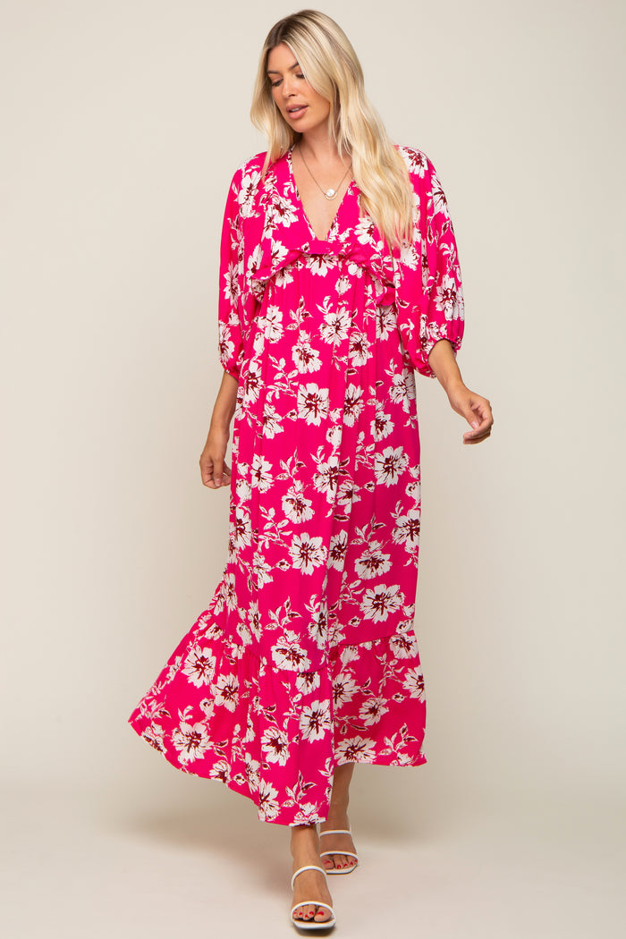 woman wearing a pink floral maxi dress with a v-neck and puff sleeves, standing in a relaxed pose