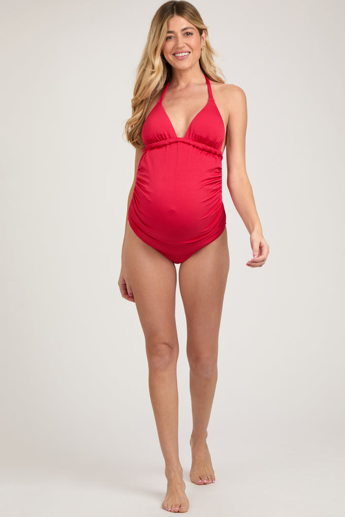 woman wearing a red halter neck maternity swimsuit and showing her baby bump