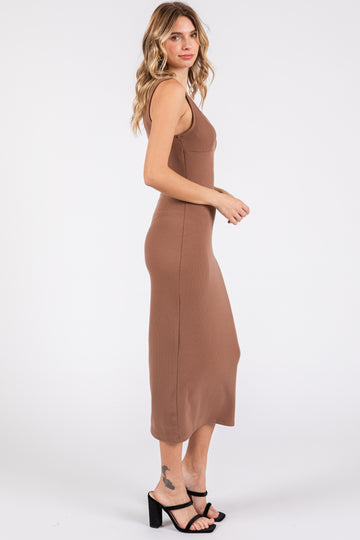 woman wearing a fitted brown ribbed midi dress with a scooped neckline and side slit, standing sideways