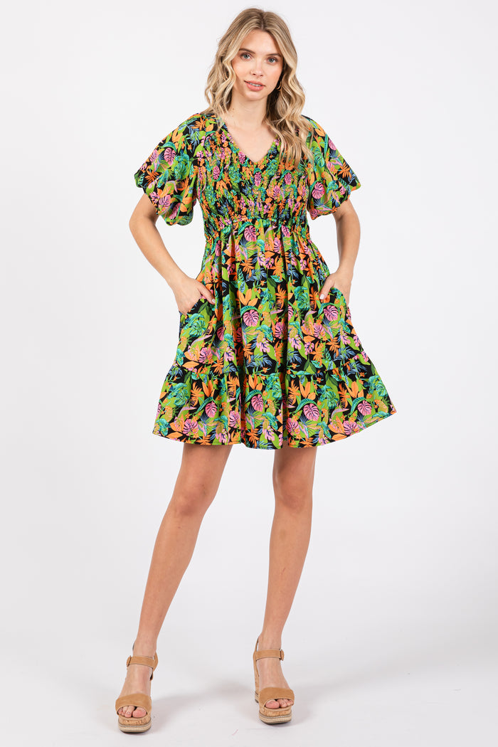 woman wearing a vibrant green floral short dress with puff sleeves and pockets, standing in a relaxed pose