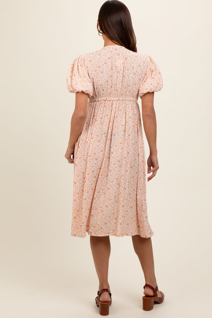 woman wearing a pastel floral maternity dress with puff sleeves and a gathered waist, shown from the back