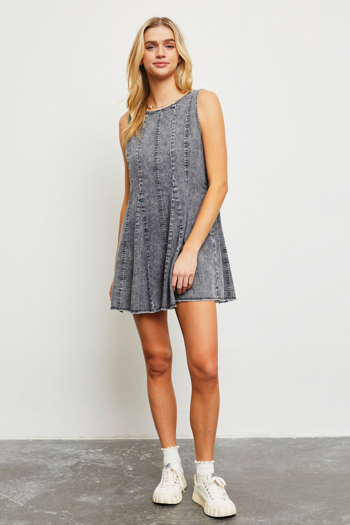 woman wearing a gray sleeveless denim dress with a flared hem and frayed edges
